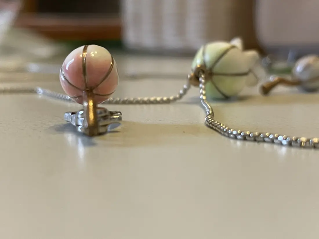 Boccioli smaltati montati su catenella a sfere: rosa e verde, nervature a vista.