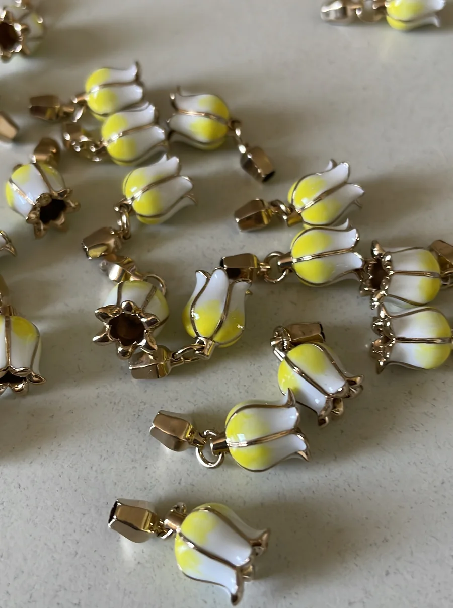 La minuteria finita: ottone dorato e smalto bianco e giallo, una campanula per ogni maglia.